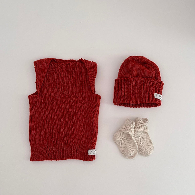 Baby burnt orange vest, beanie, and socks on a light background