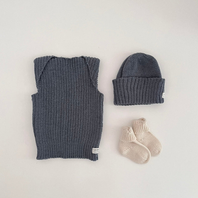 Baby dusky blue vest, beanie, and socks on a light background