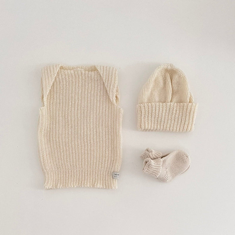Baby ivory vest, beanie, and socks on a light background