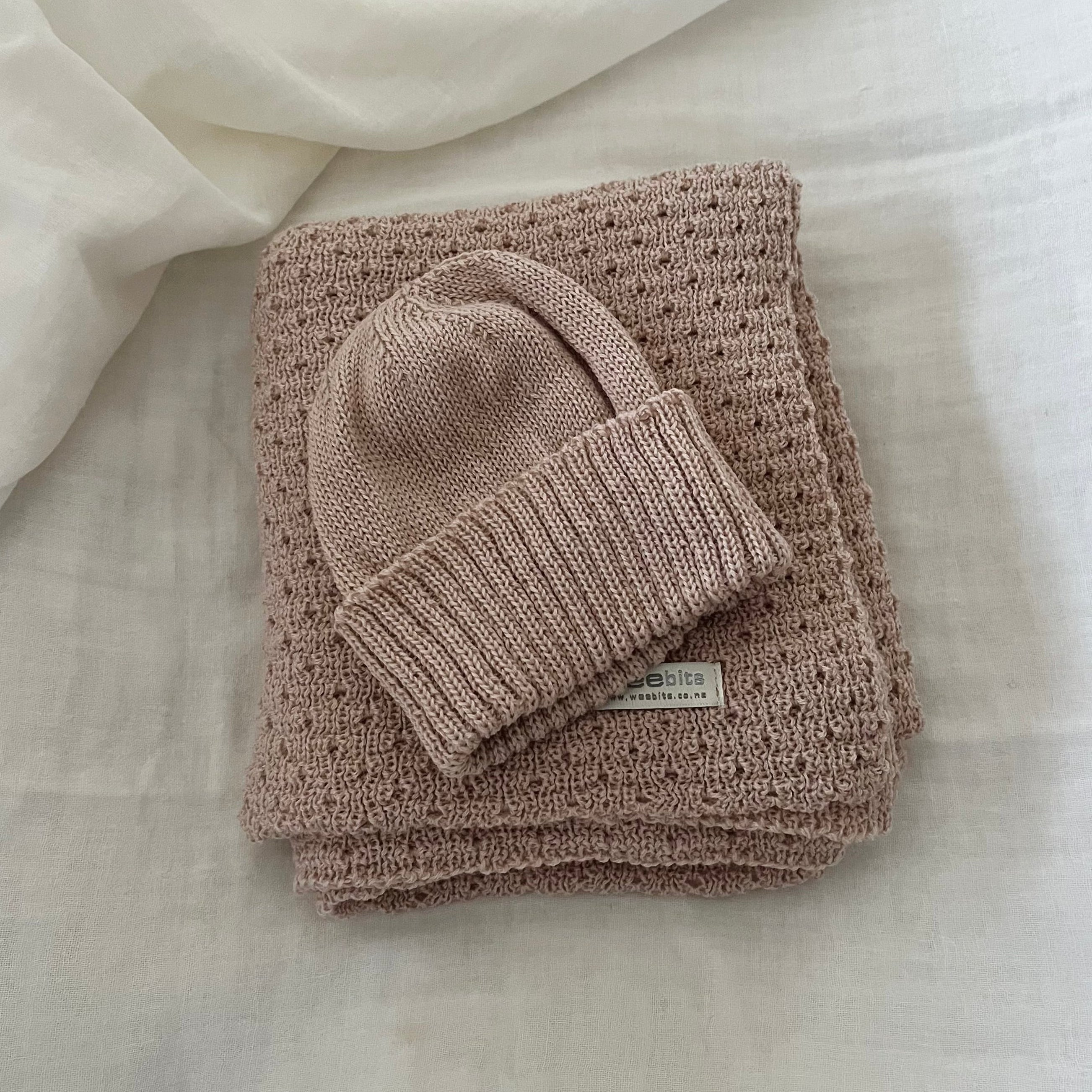 Folded  sandstone baby wrap with a matching beanie on a light fabric background