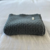 Dusky blue merino baby wrap on cotton sheet