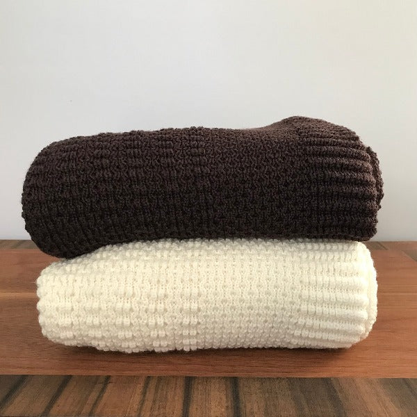 Merino cot blanket stack chocolate and ivory on table