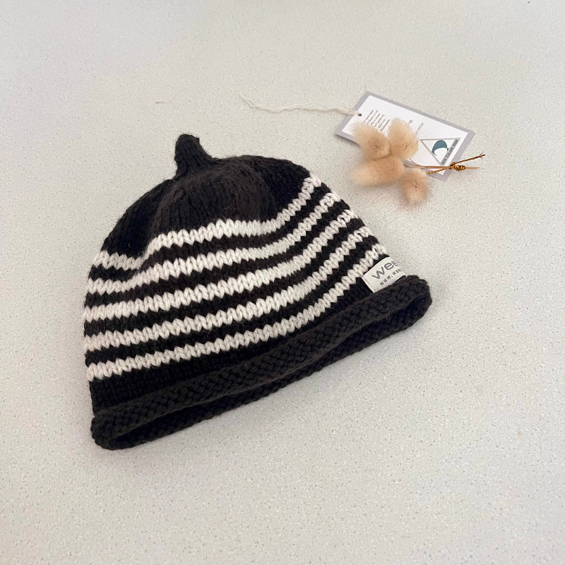 Chocolate with natural striped knit baby hat with a tag on a light grey background