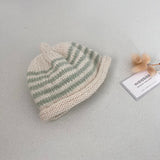 Natural and mint striped knit baby hat with a tag on a light grey background