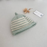 Mint and natural striped knit baby hat with a tag on a light grey background