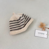 Natural and mushroom striped knit baby hat with a tag on a light grey background