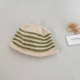 Natural and pistachio striped knit baby hat with a tag on a light grey background