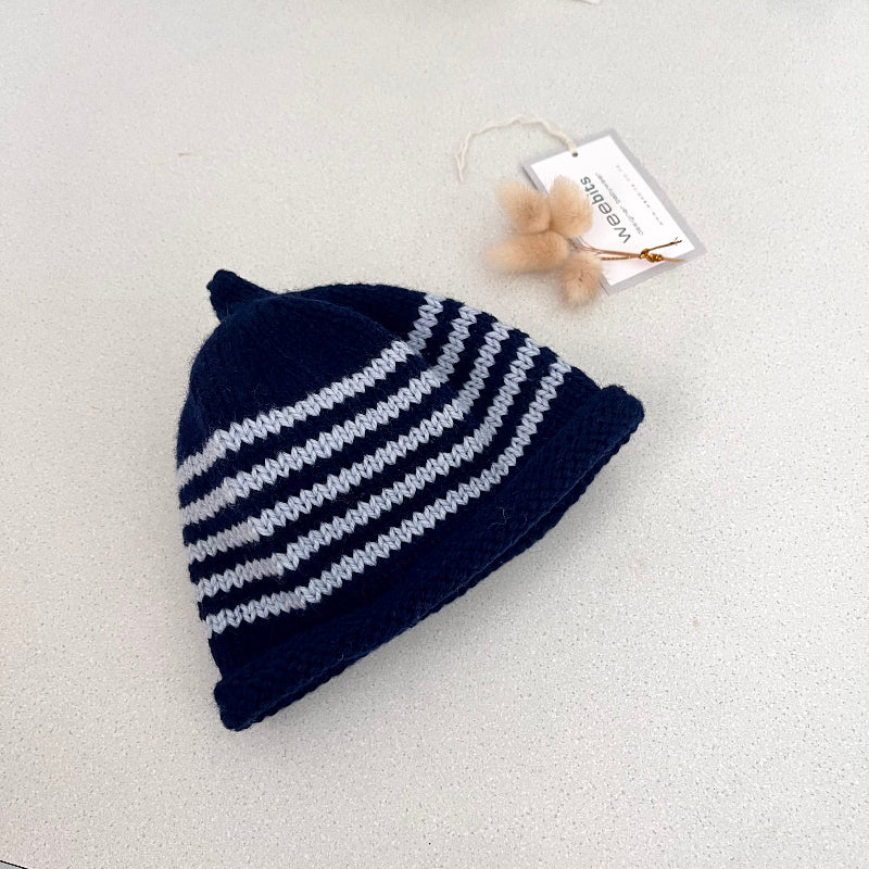 Navy and blue striped knit baby hat with a tag on a light grey background