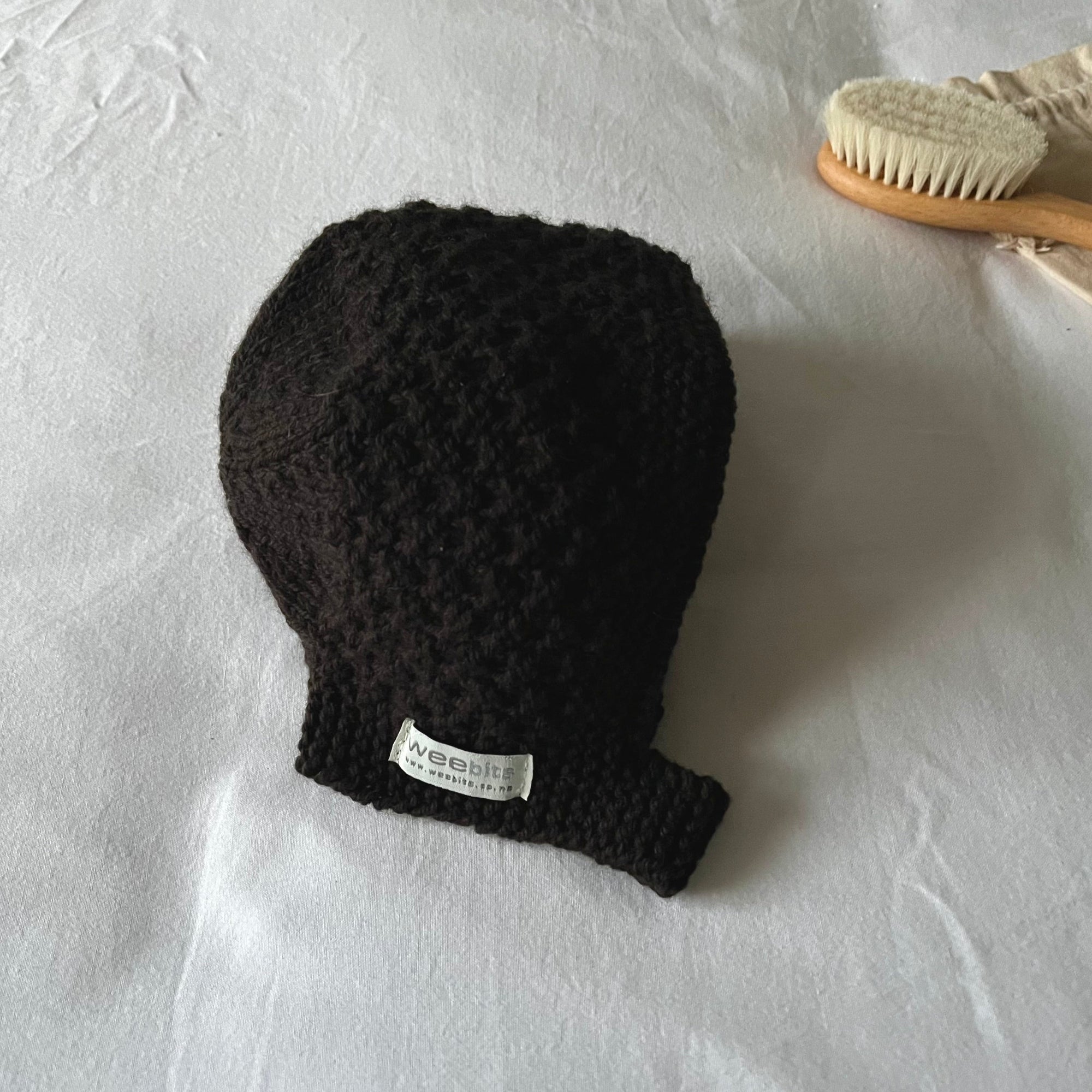Chocolate knitted baby hat with a label on a white background
