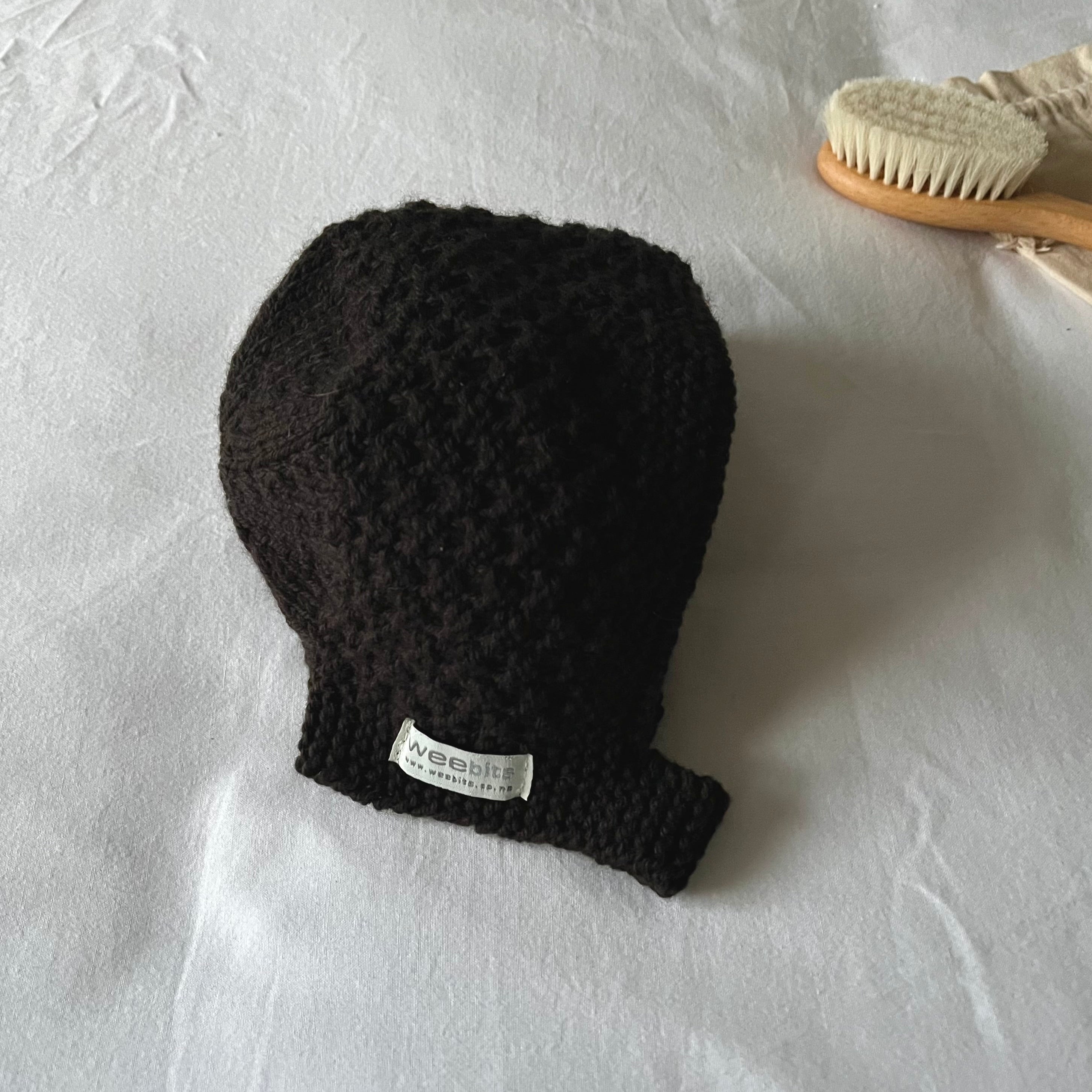 Chocolate knitted baby hat with a label on a white background