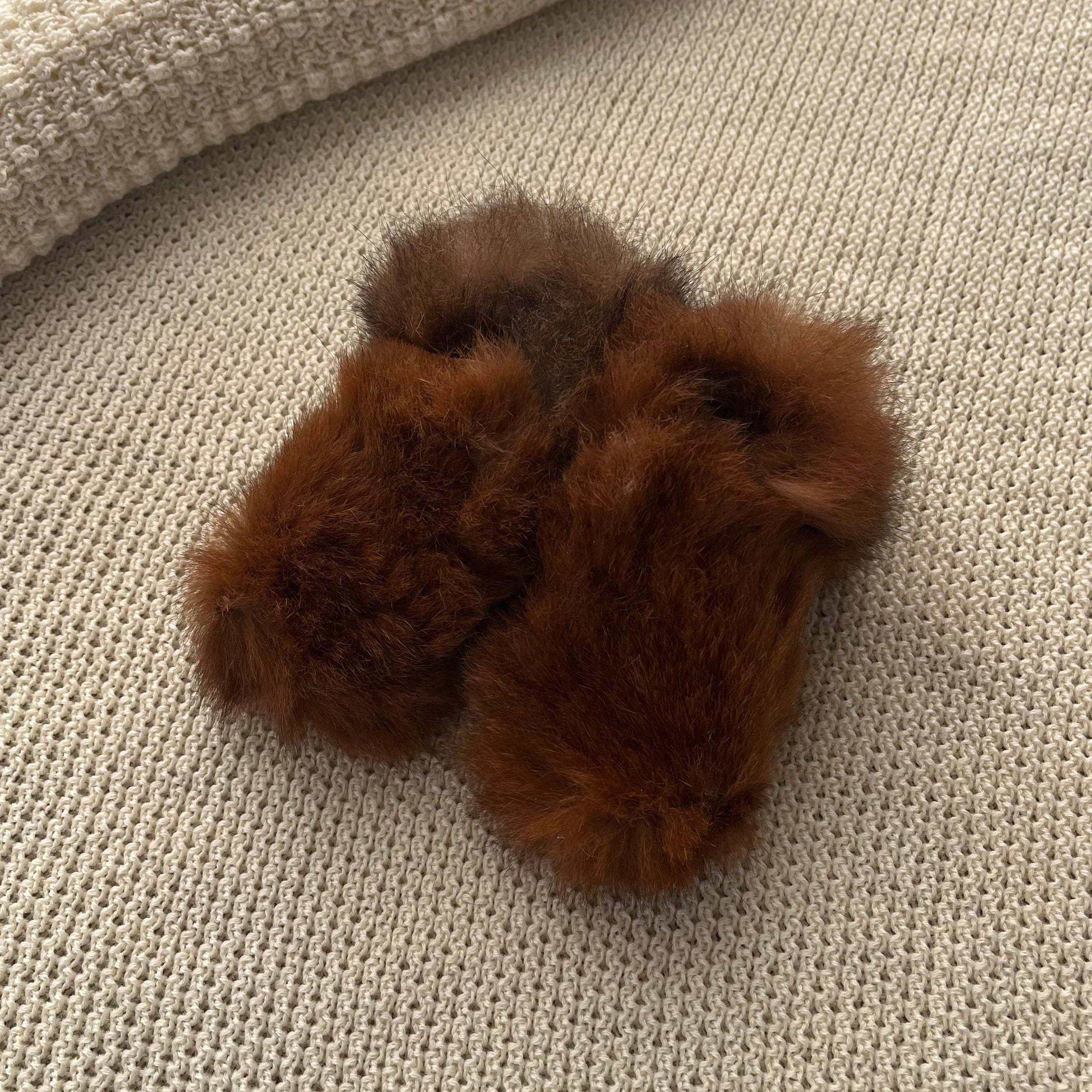 Brown fuzzy possum boots on a textured beige surface