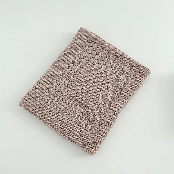 Knitted sandstone pram blanket on a light gray background