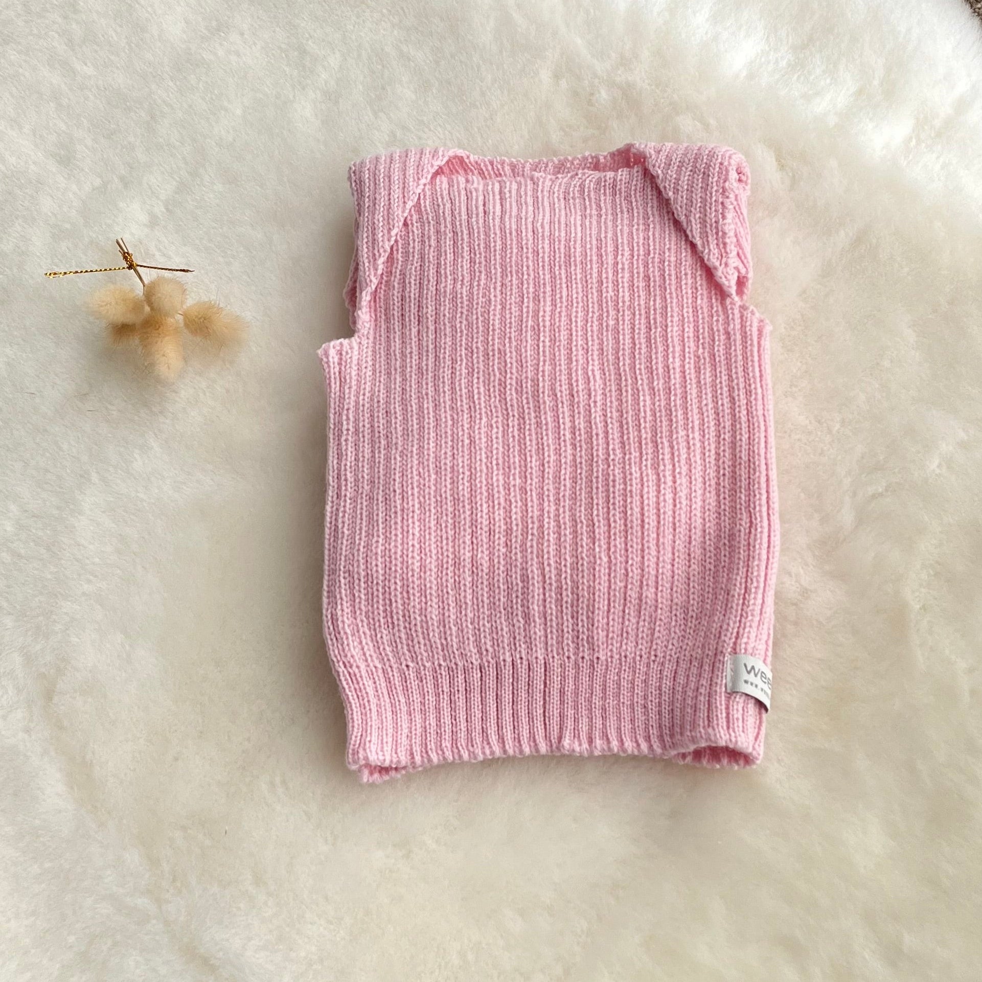 Blossom pink premature baby vest on sheepskin rug