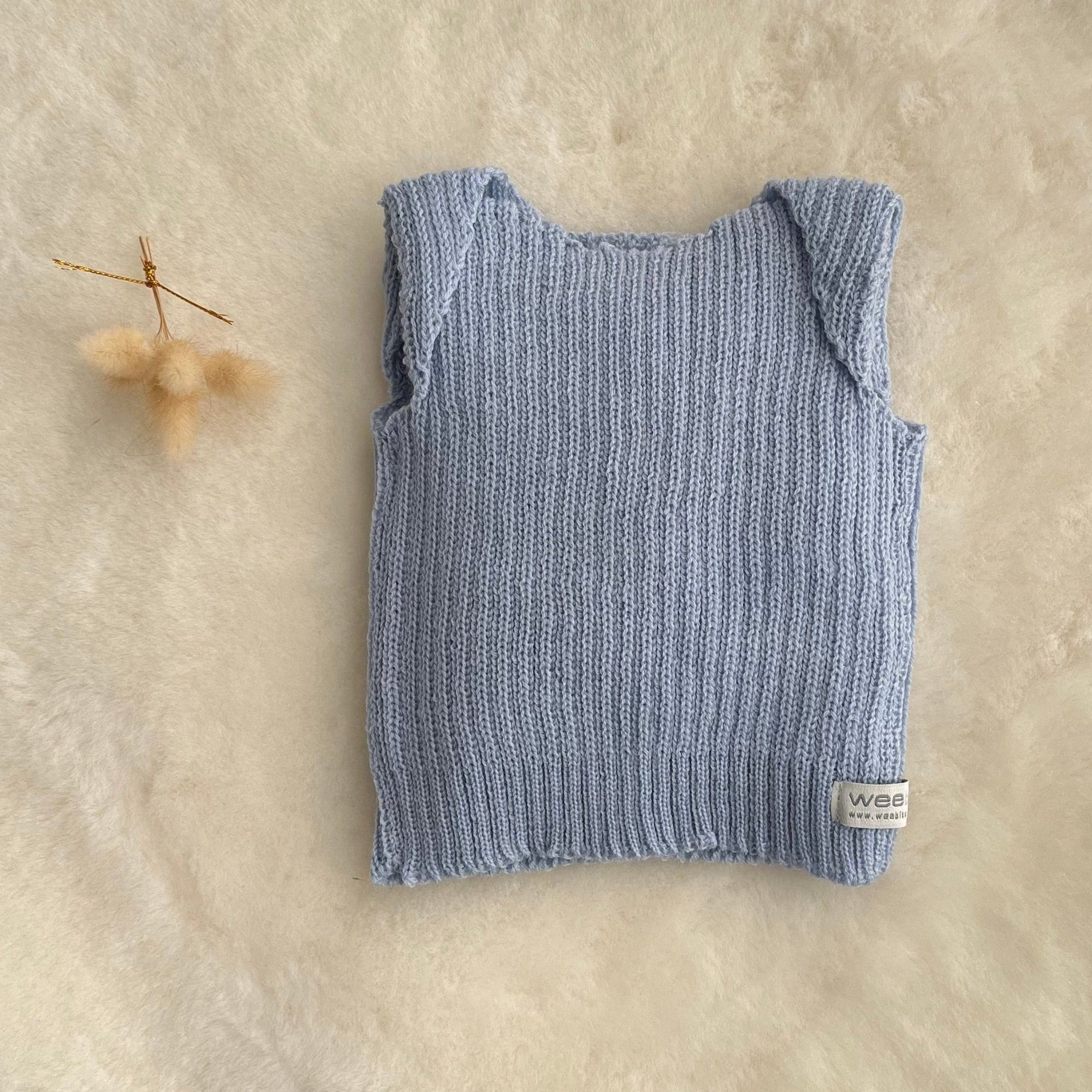 Blue premature baby vest on sheepskin rug