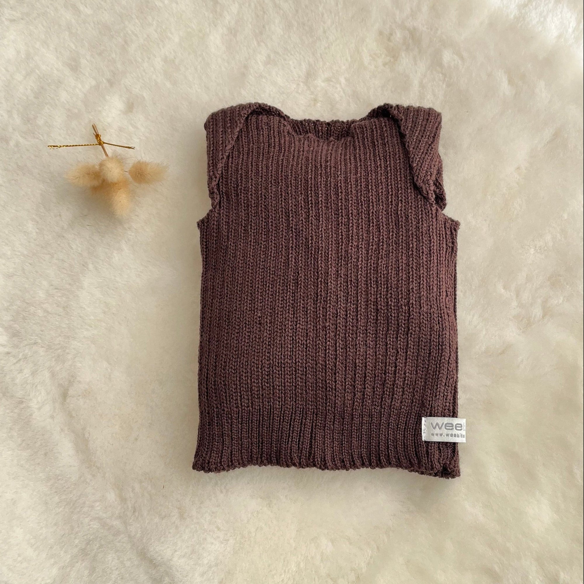 Brown premature baby vest on sheepskin rug