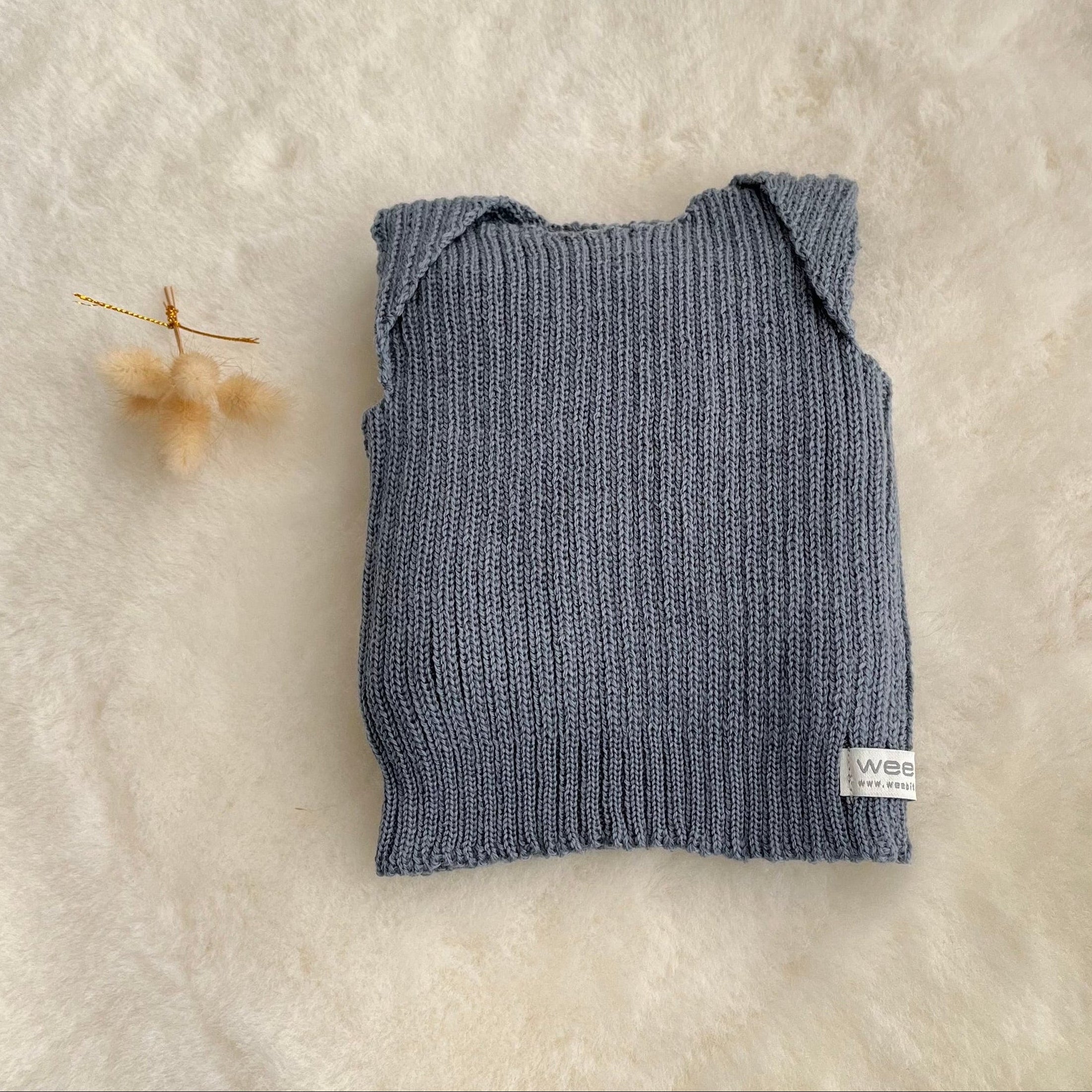 Dusky blue premature baby vest on sheepskin rug