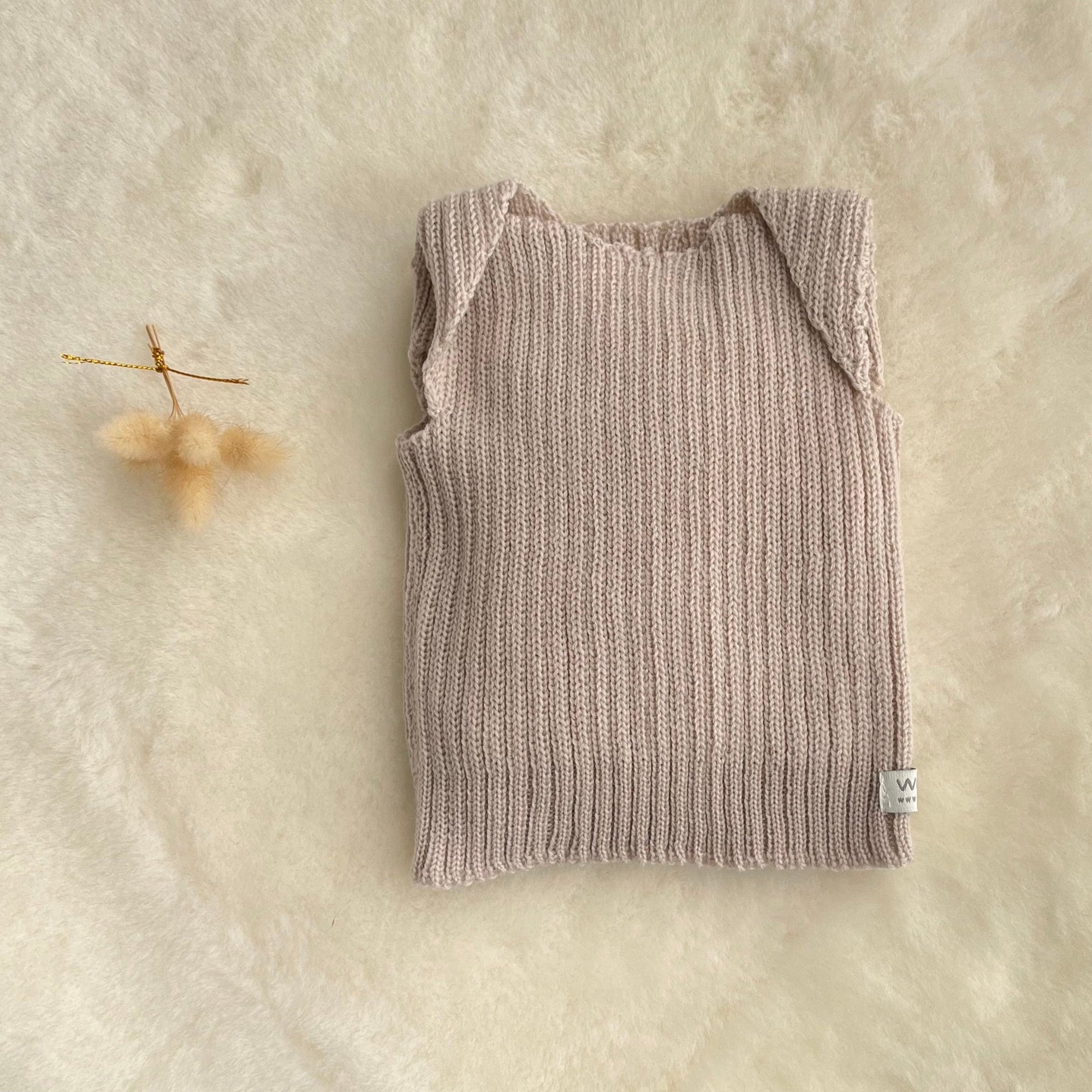 Oatmeal premature baby vest on sheepskin rug