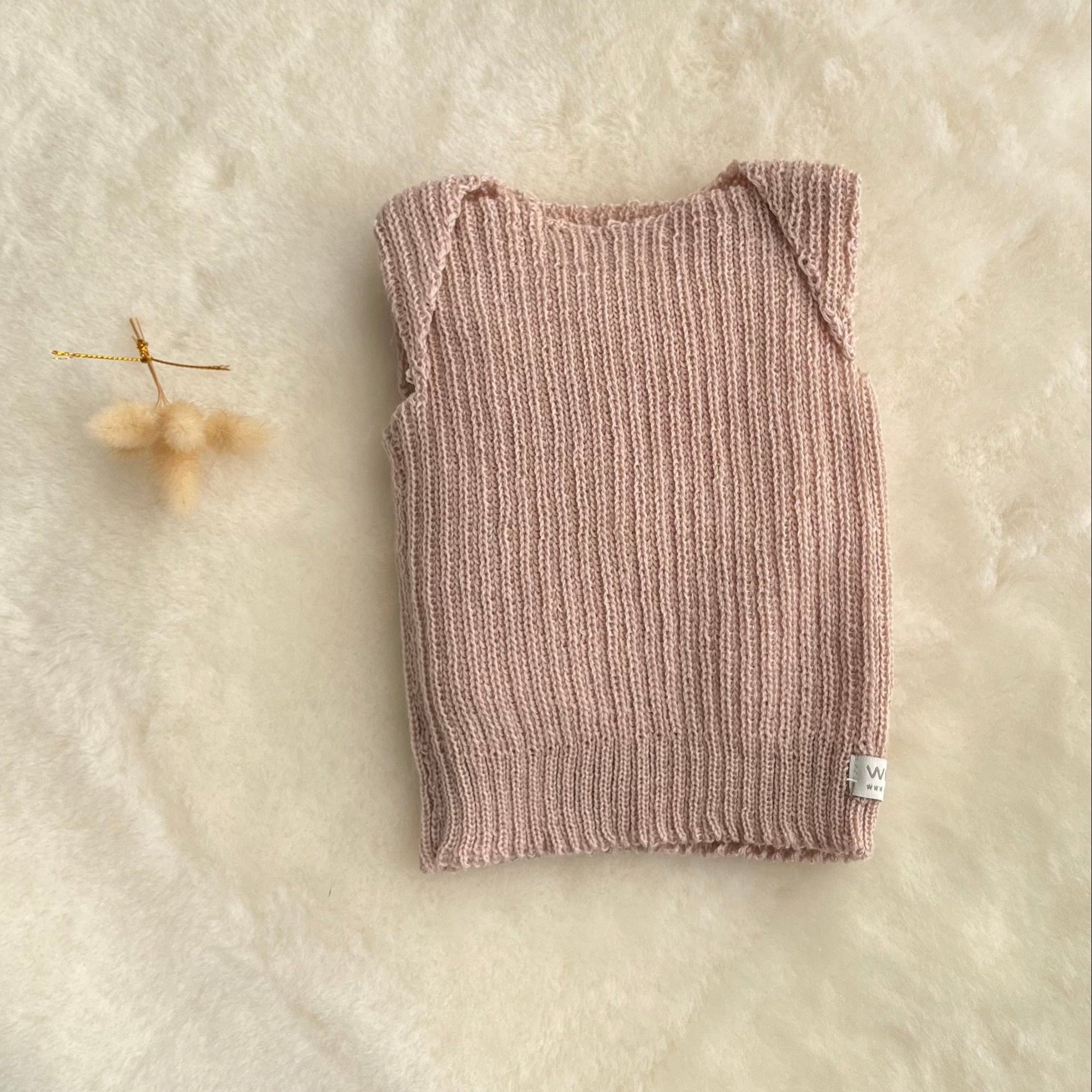 Sandstone premature baby vest on sheepskin rug