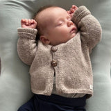 Premature baby wearing knitted oatmeal cardigan