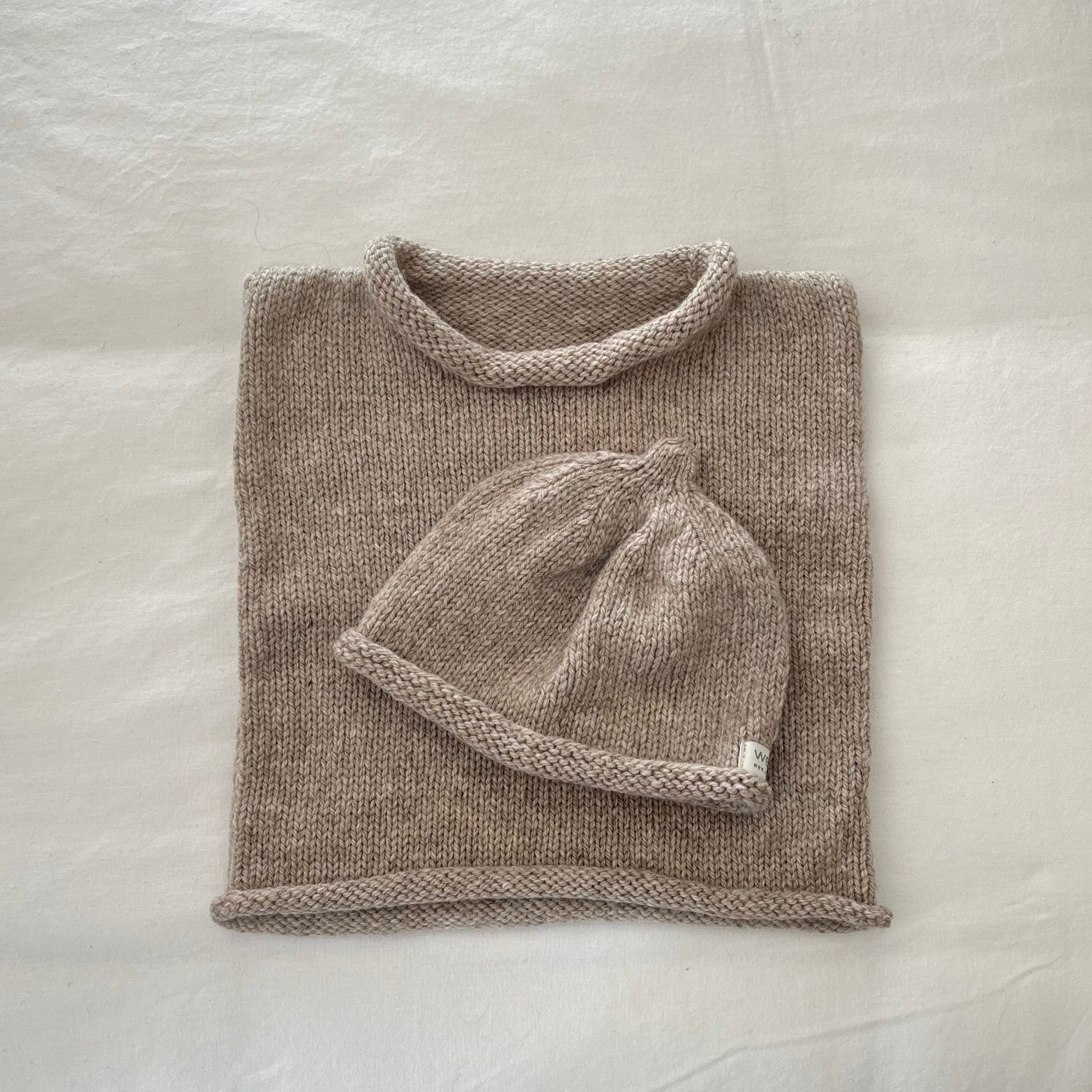 Knitted oatmeal baby vest and hat set on a white background