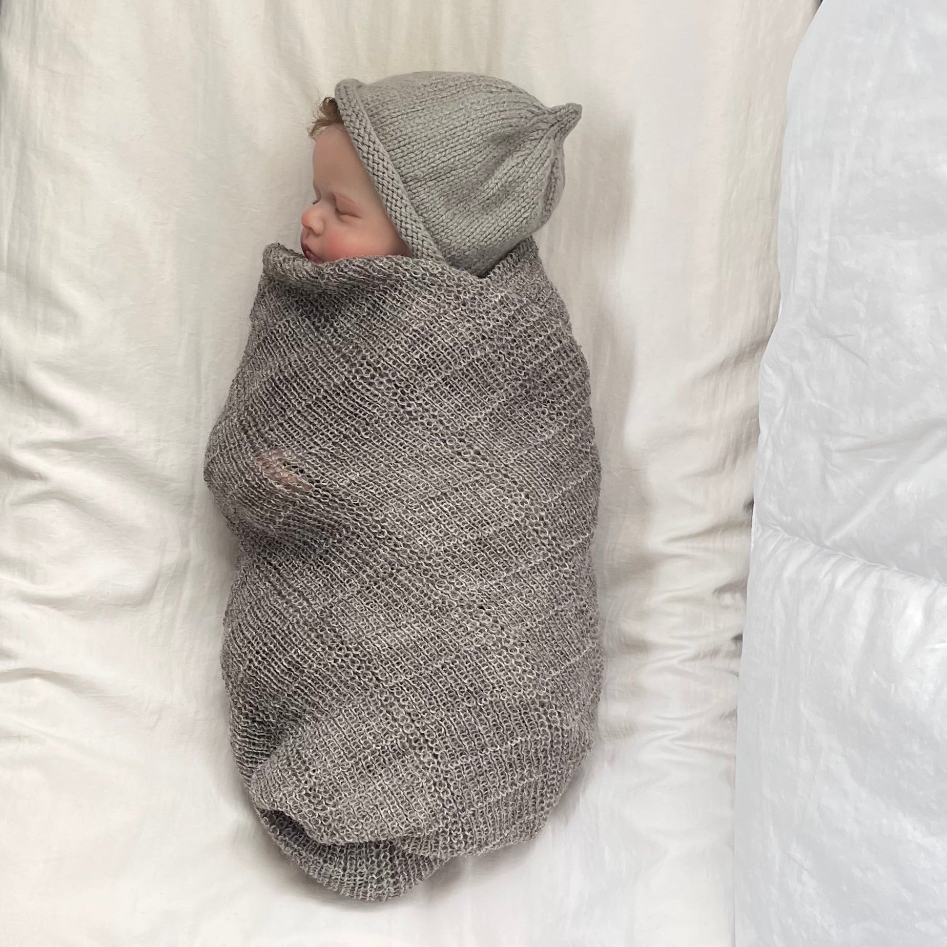 sleeping baby in knitted stansborough baby wrap and beanie