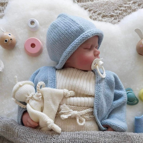 Sleeping baby wearing blue cardigan beanie set