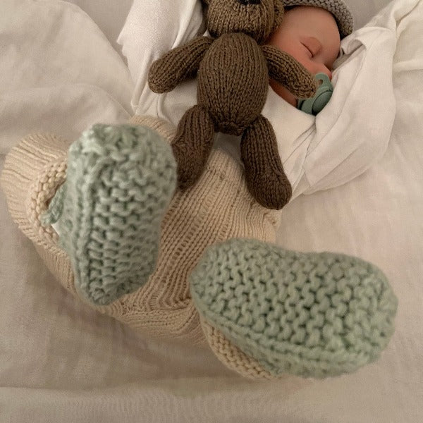 sleeping baby wearing chunky knit booties in mint