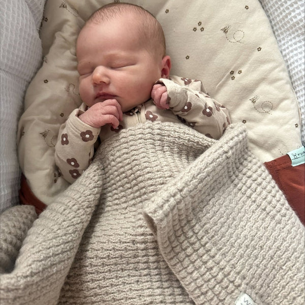 Sleeping baby wrapped in pram blanket