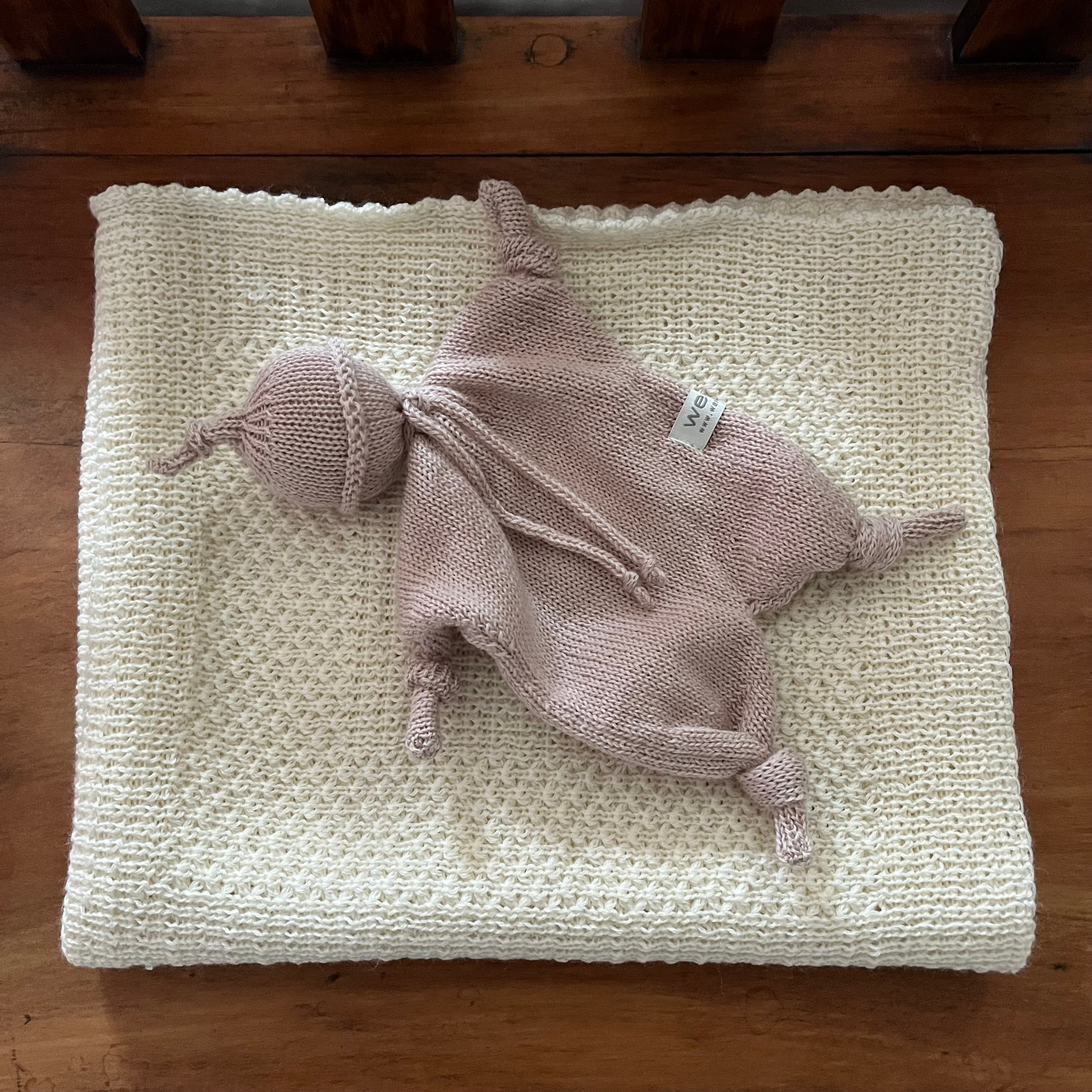 Sandstone knitted baby comforter on textured beige surface