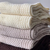 Stack of merino knit bassinet blankets ivory and oatmeal
