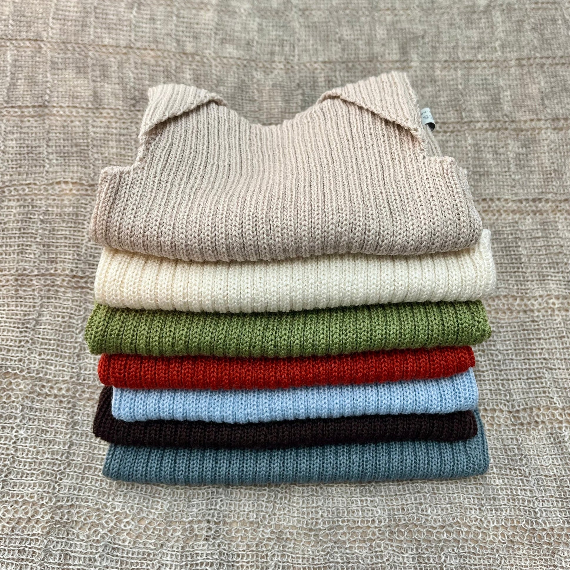 Stack of coloured merino baby singlets
