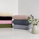 Stack of merino baby wraps on a white bench with flowers