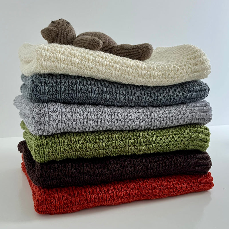 Teddy on a stack of merino bassinet blankets