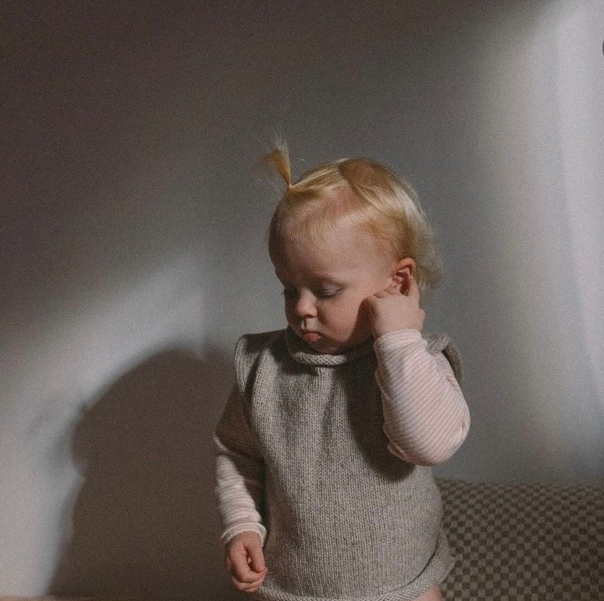 Little girl wearing an oatmeal roll neck vest and pink stripe shirt 