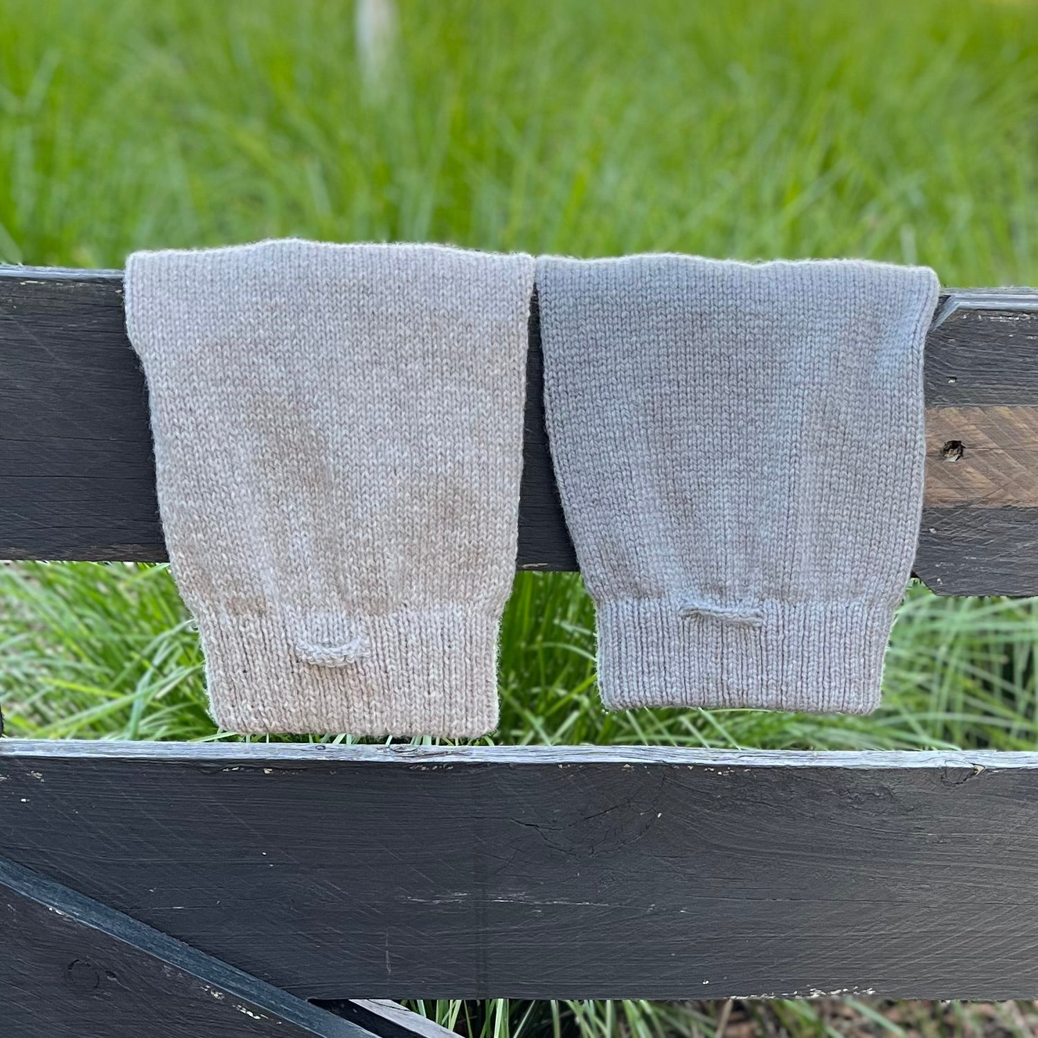 Two merino knitted dog jumpers draped over fence with top showing