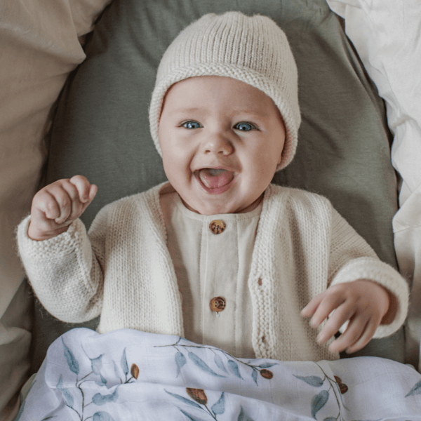 Baby wearing natural baby cardigan and beanie set