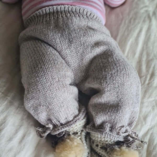Baby wearing oatmeal knitted pants with ankle ties