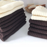 Stack of ivory and brown baby singlet vests